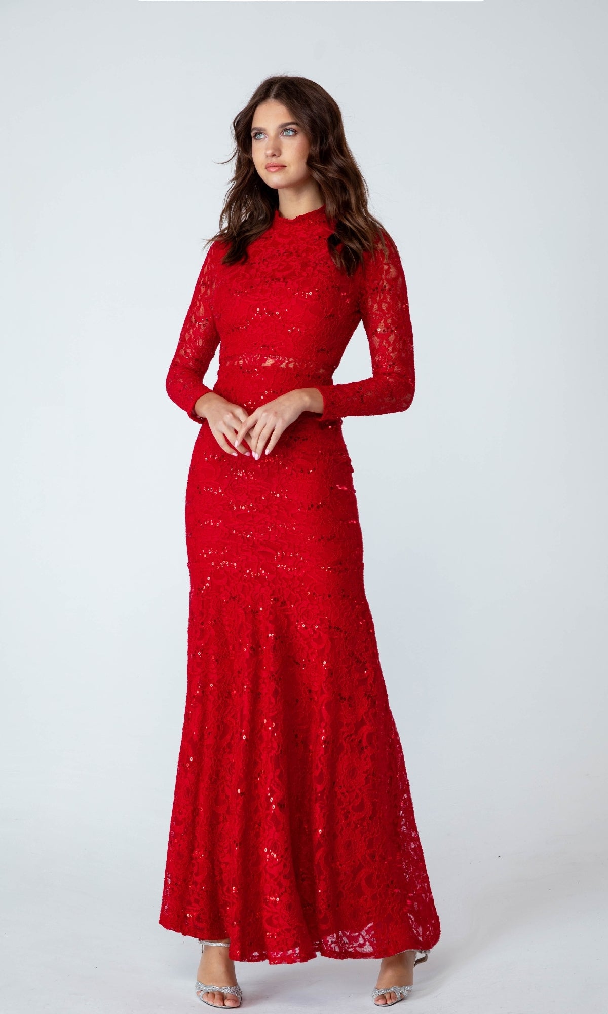 A woman in the affordable Eureka 2095 Long Sleeve Sequin-Lace Formal Dress—floor-length and red—pairs it with silver heels, posing against a plain light background.
